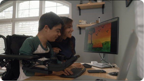  A VILTEPSO patient, and caregiver smiling while working together on a digital painting displayed on a computer screen.