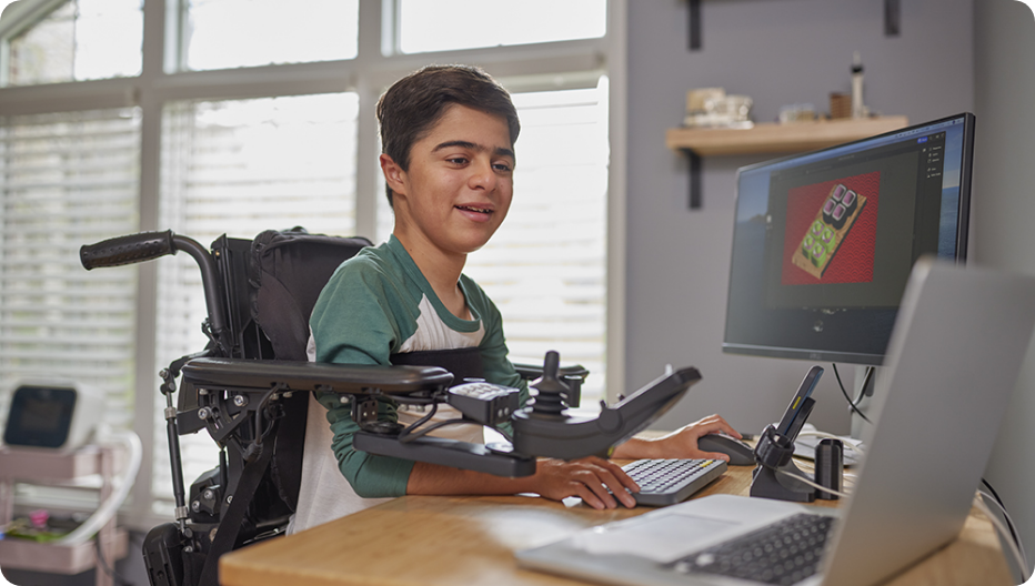 A VILTEPSO patient in a wheelchair using an adaptive workstation to create 3D designs on a computer.
