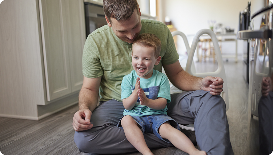 Roland sitting on his father's lap indoors